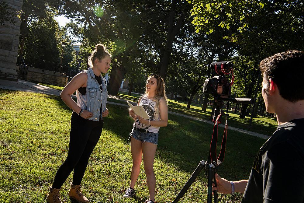 Two students practice an on-camera interview, while a third manages the camera.